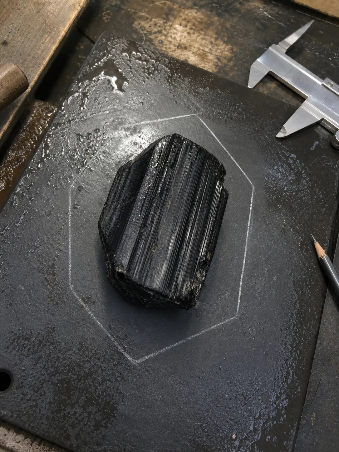 Planning view of a black tourmaline piece with preserved surface character and a readable hexagon direction