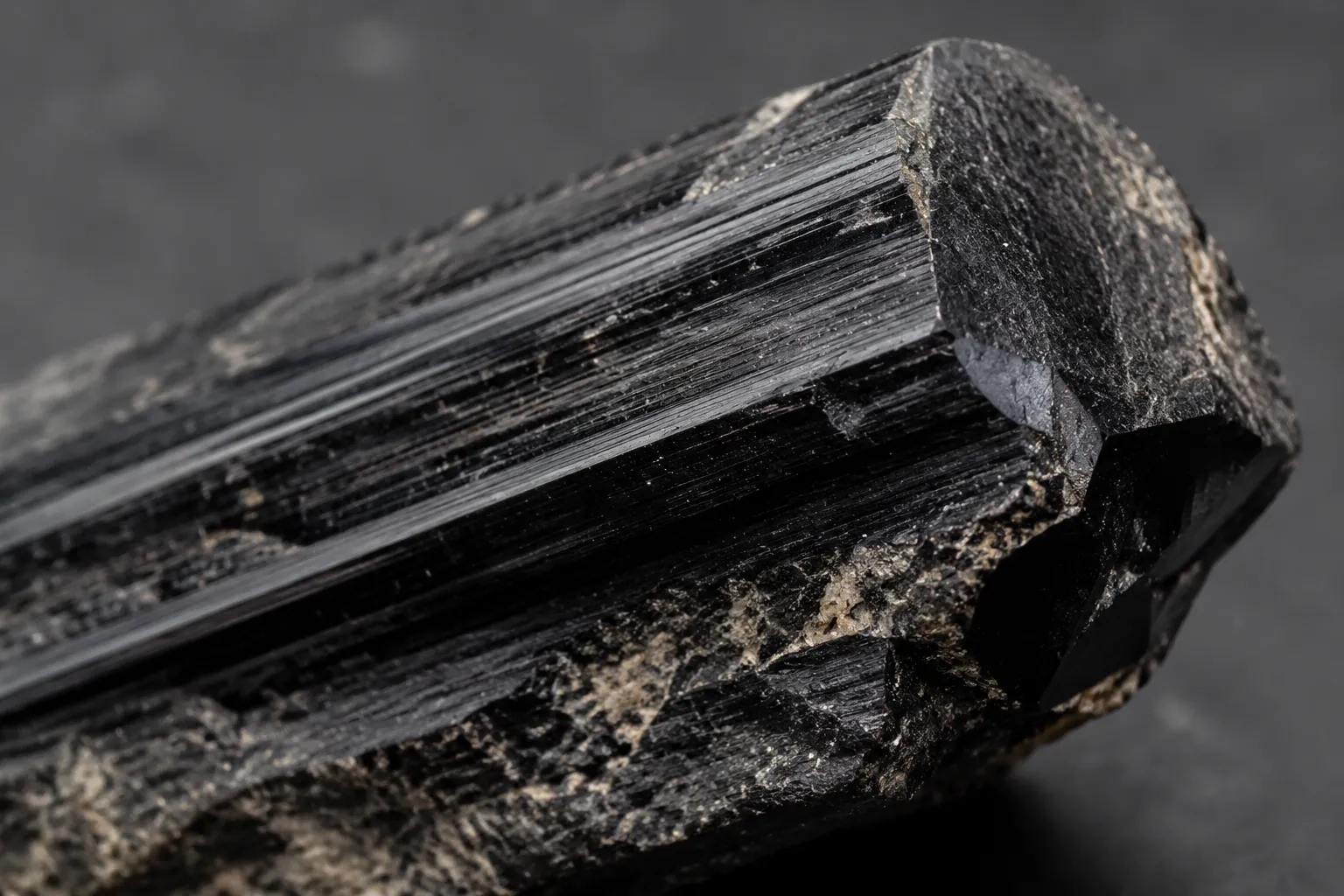 Close view of black tourmaline natural faces, striations, and a termination as specimen features that can be softened by polishing