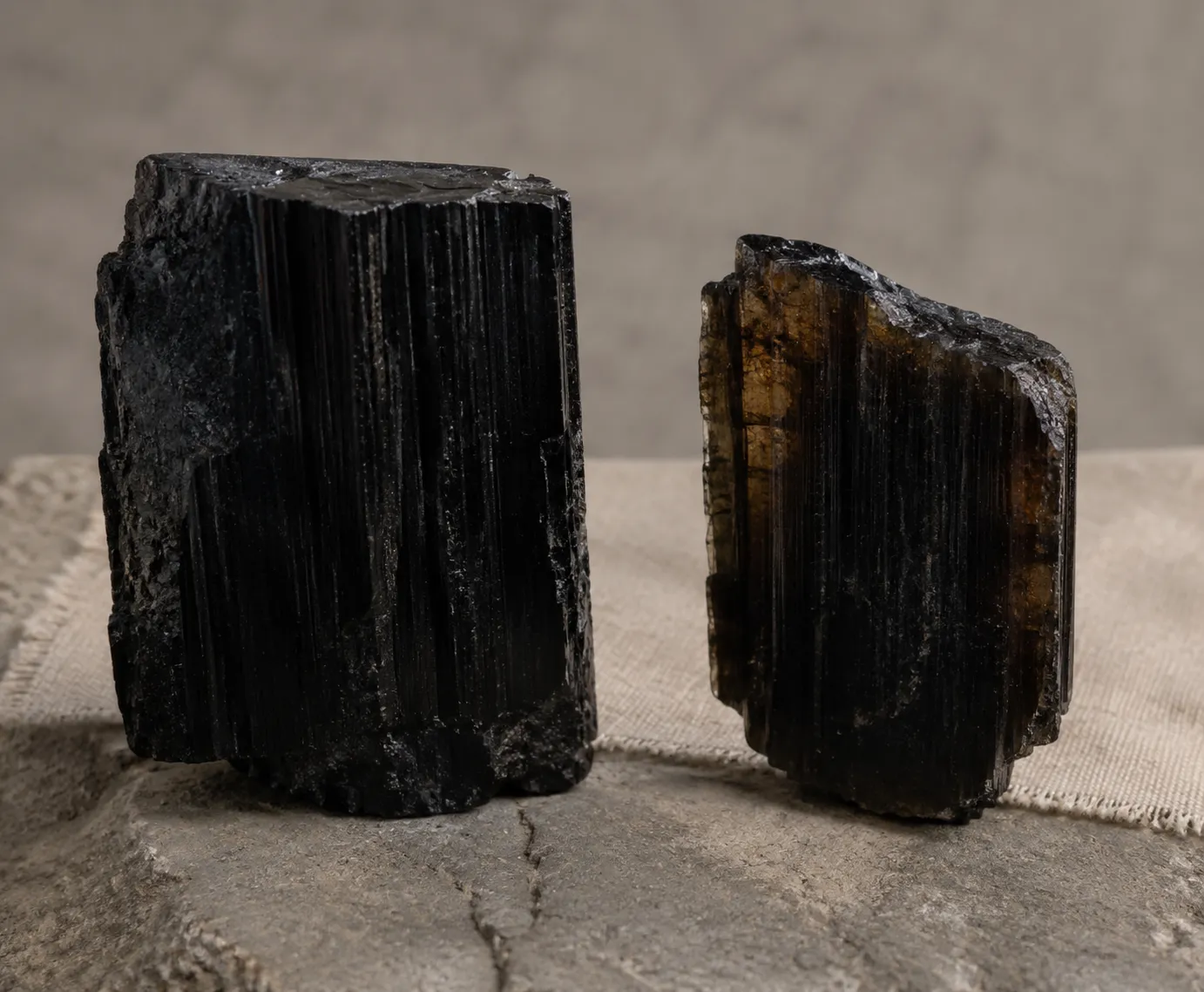 Two black tourmaline specimens with one showing a lighter edge under backlight.