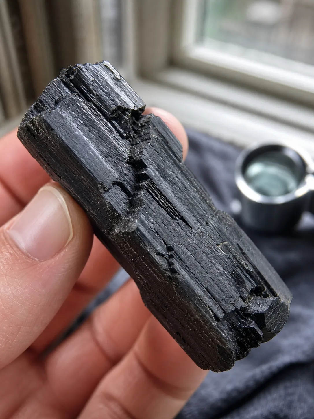 Close observation of a black tourmaline edge showing angular breaks, lengthwise ridges, and the limit of home screening
